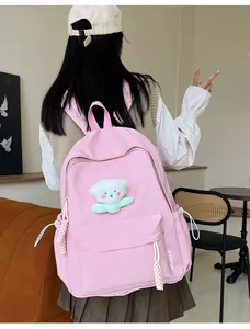 Sac à dos rose décontracté avec breloque peluche blanche porté par un mannequin
