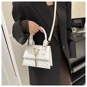 Dettaglio borsa trapuntata bianca con logo a V dorato, nappa e tracolla rimovibile