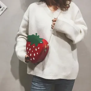 Détail du sac à bandoulière fraise rouge avec rabat feuille verte et chaîne dorée