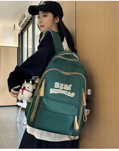 Side view of dark green backpack featuring khaki trim and a cute white bear pendant