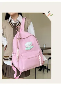 Vue détaillée du sac à dos en toile rose avec peluche et tirettes de fermeture tissées