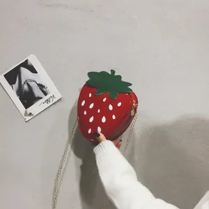 Détail du sac bandoulière fraise en cuir verni rouge avec sa chaîne dorée élégante