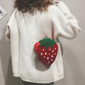 Détail du sac à bandoulière fraise créatif avec finition rouge brillant et chaîne dorée