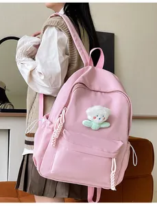 Sac à dos rose minimaliste avec breloque ours en peluche porté de profil par un mannequin