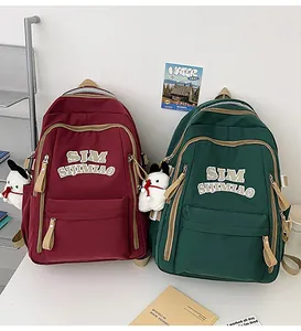 Close-up of dual burgundy and green nylon school backpacks with decorative plush charms