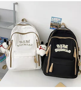 Detail of Korean style backpacks in cream and black with cute plush charms and embroidery