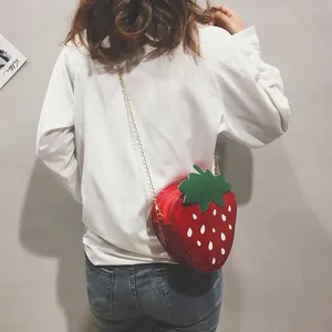 Détail du sac à bandoulière fraise rouge avec finition brillante et chaîne dorée