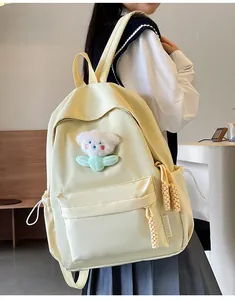 Détail d'un sac à dos en nylon crème avec ours en peluche et étiquette mode porté par un mannequin