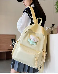 Détail du sac à dos en nylon jaune clair avec charm fleur en peluche et tirette en corde