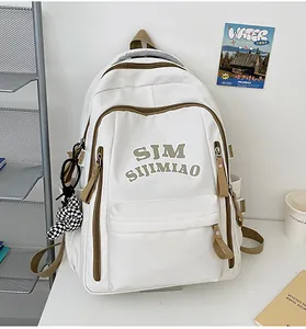 Close-up of beige waterproof backpack with brown contrast trim and checkerboard bunny charm