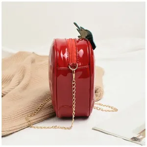 Vue détaillée du sac fraise rouge brillant avec décor de feuilles et chaîne dorée