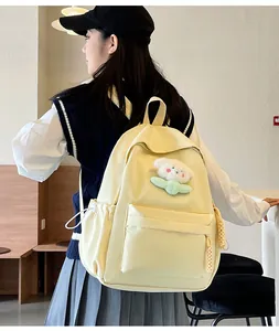 Détail d'un sac à dos en toile crème avec un joli petit ours en peluche blanc accroché