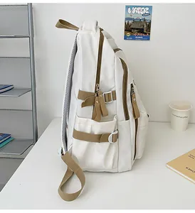 Detail of white canvas backpack side view with khaki adjustable straps and metal rings