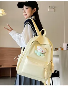 Détail d'un sac à dos en toile jaune pâle avec poche latérale à cordon et pendentif ours
