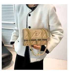 Dettaglio borsa trapuntata beige con tracolla a catena dorata e ciondolo a nappa