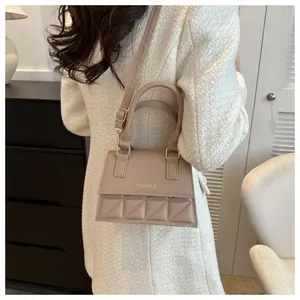 Beige gesteppte kleine quadratische Umhängetasche an einem Model in minimalistischer Umgebung