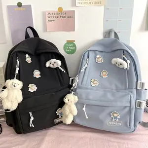 Detalle de mochilas escolares de nailon negro y azul con osito y parches lindos