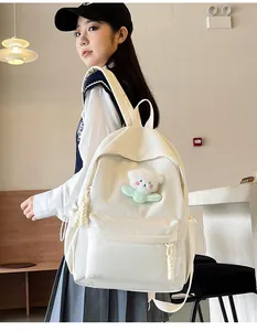 Détail du sac à dos en nylon blanc crème avec breloque ours en peluche et poches à cordon