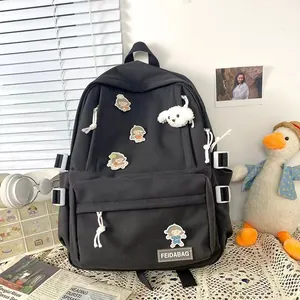 Detalle de la mochila negra Harajuku con insignias de dibujos y un colgante de peluche