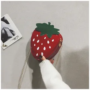 Détail du sac bandoulière fraise créatif avec finition brillante et chaîne dorée