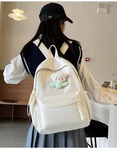 Gros plan du sac à dos en nylon blanc avec porte-clé ours peluche et poche latérale à cordon