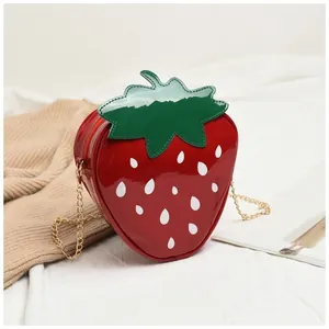 Détail du sac bandoulière fraise rouge avec chaîne dorée et feuilles vertes réalistes