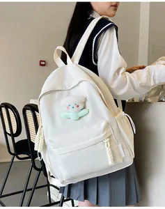 Détail d'un sac à dos blanc en nylon avec charm d'ours en peluche et étiquette de mode
