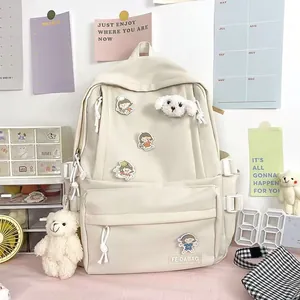 Detalle del primer plano de la mochila de nailon crema con parches de dibujos y peluche