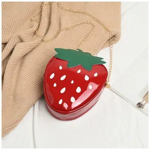 Détail du sac bandoulière fraise sur pull avec bandoulière chaîne dorée