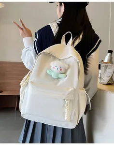 Détail d'un sac à dos blanc en nylon avec un ours en peluche 3D et des fermetures en corde