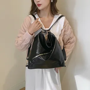 Bolso tote negro brillante de gran capacidad llevado por una modelo con ropa casual