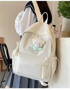 Détail du sac à dos blanc en nylon avec un charm ours en peluche et tirettes en corde