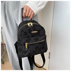 Detail of black mini backpack featuring floral texture and golden metal hardware accent