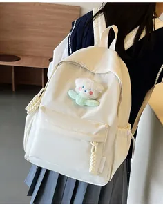 Photo portée du sac à dos blanc minimaliste avec pendentif ours et étiquette