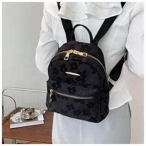 Detail of black mini backpack featuring embossed floral texture and gold zippers