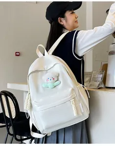 Détail d'un sac à dos en nylon blanc avec un ours en peluche et zip en corde tressée