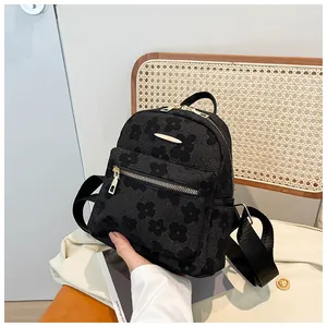 Detail of black mini backpack with floral relief texture and golden zipper accents