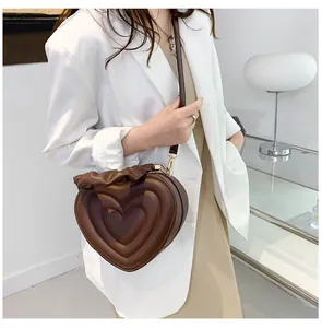 Close-up of heart-shaped handbag featuring brown faux leather and ruffled trim details