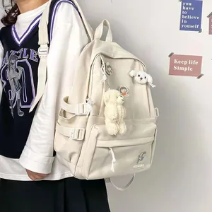 Detalle de la mochila minimalista de nailon blanco crema con colgantes y hebillas laterales