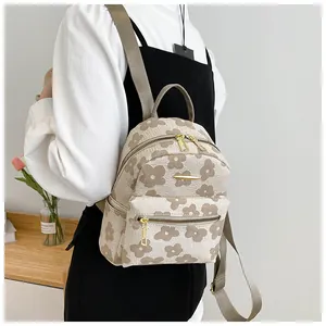 Detailed back view of a compact floral backpack worn by a model in a minimalist room