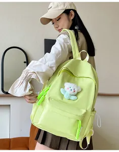 Détail d'un sac à dos en nylon vert clair imperméable avec un pendentif ours en peluche