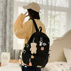 Detalle de mochila negra de lona multibolsillos con parches y colgante de osito