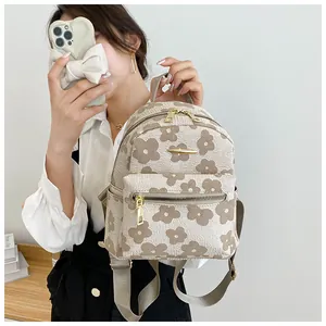 Detail of floral printed mini backpack showing golden metal zippers and front pocket