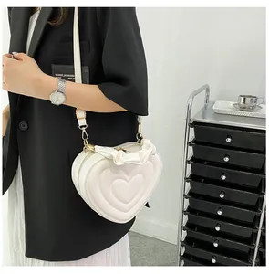 Detail of a beige heart-shaped bag with ruffled edges and quilted texture on a model
