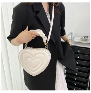 Chic white heart-shaped crossbody bag with quilted pattern shown on a female model