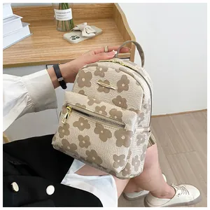Detail of floral embossed texture on cream backpack with golden metallic zippers