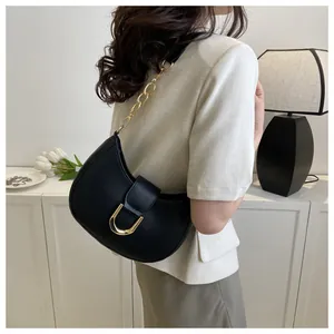 Detail of black crescent moon bag with golden U-shaped buckle and chain shoulder strap