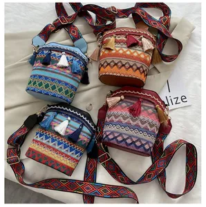 Dettaglio di quattro borse a secchiello boho colorate con motivi geometrici e nappe