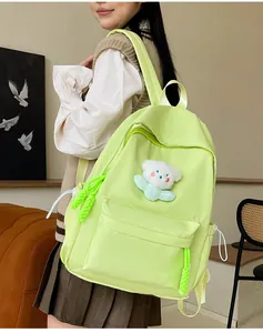 Vue détaillée d'un sac à dos en nylon vert clair avec un joli ours en peluche blanc
