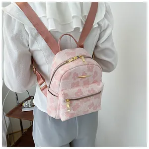 Back view of a model wearing a small pink floral backpack with gold zipper details